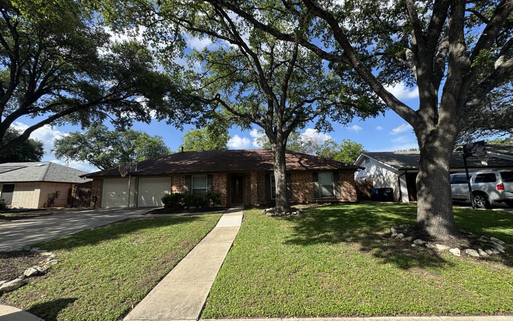 Freshly mowed, oak-framed front lawn in Converse, TX